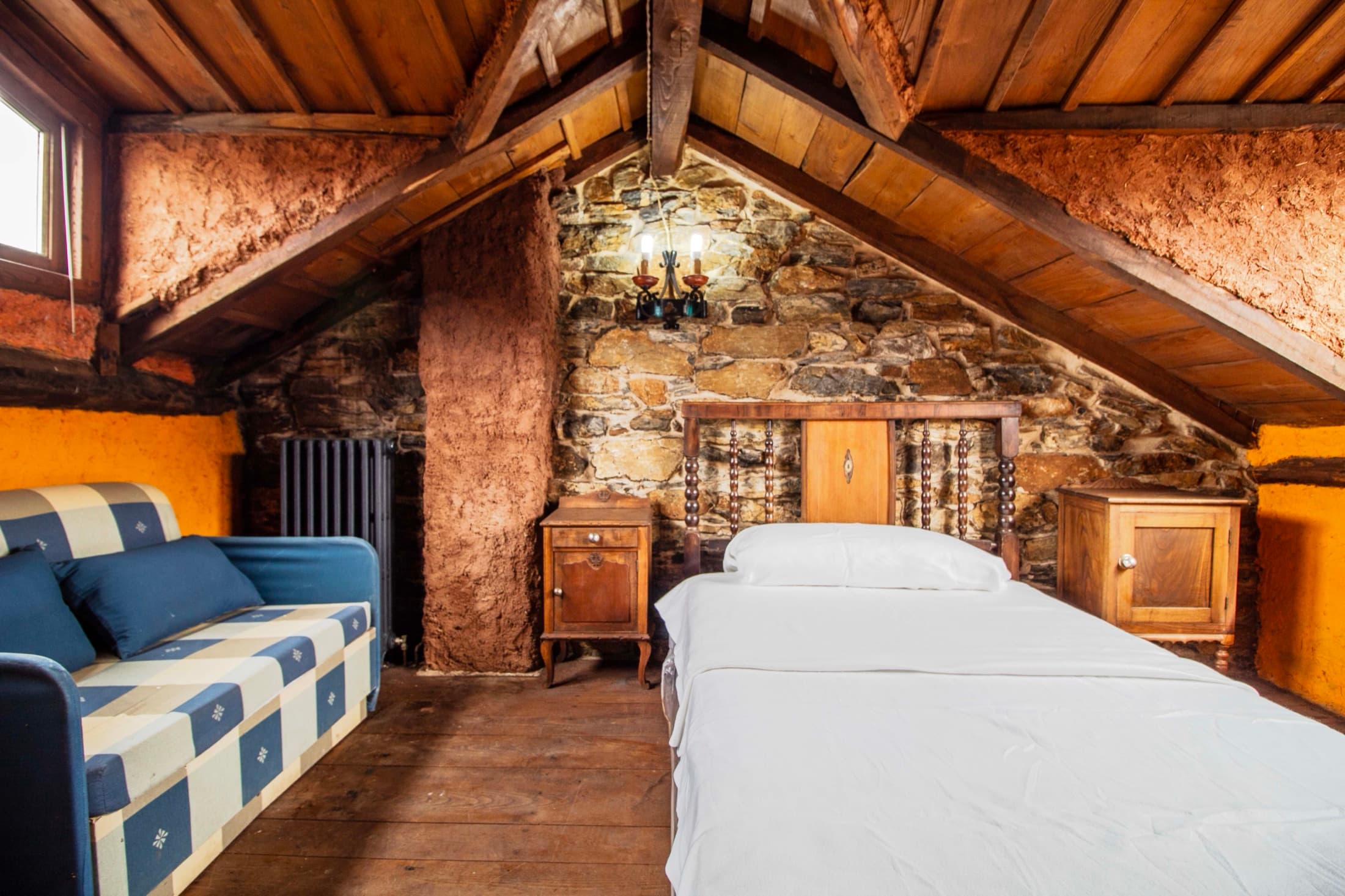 Dormitorio abuhardillado con cama y sofá cama