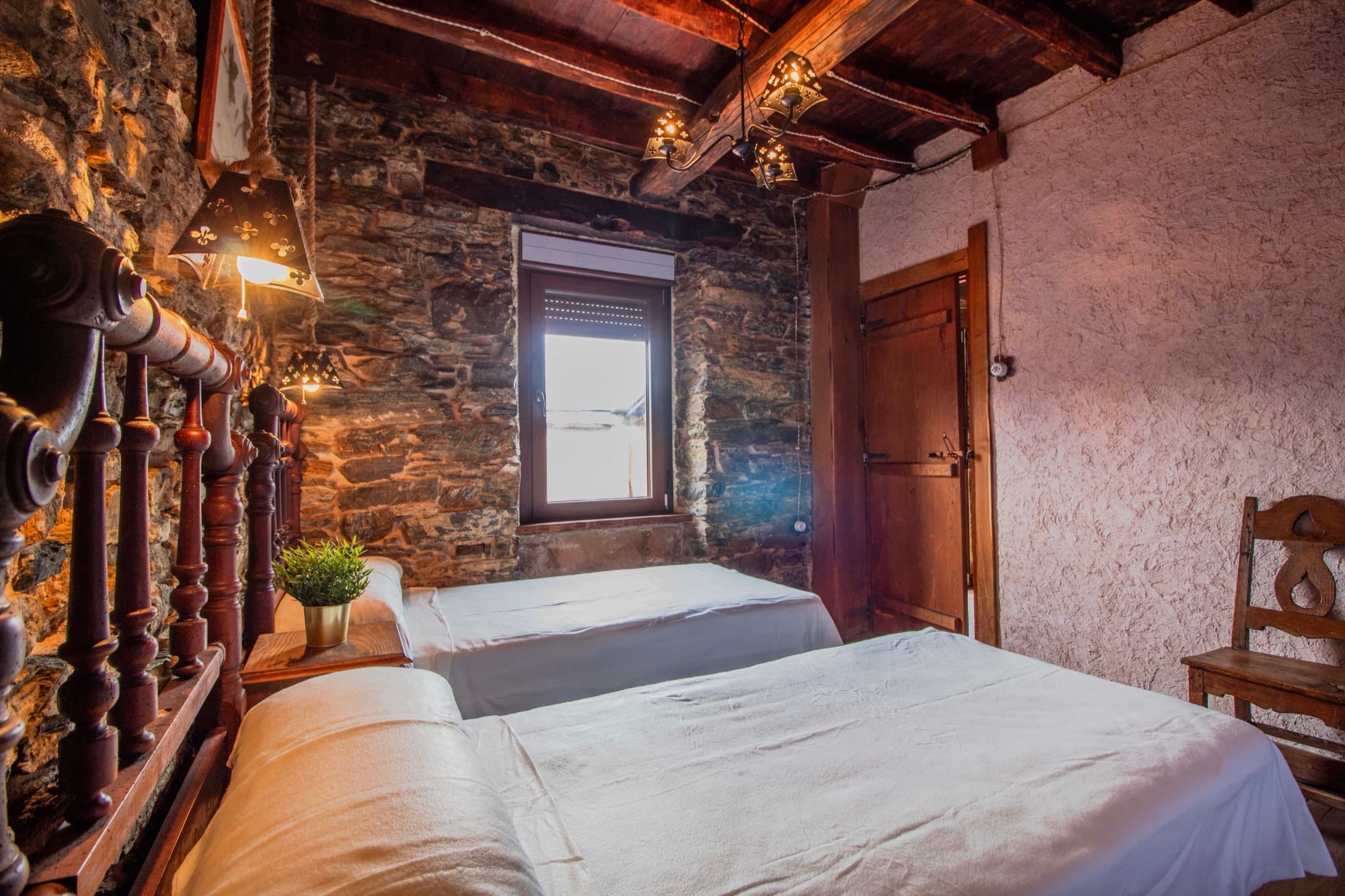 Dormitorio doble con muros de piedra y madera